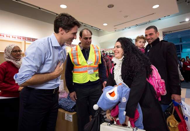 Canadian Prime Minister Justin Trudeau greets a family of refugees from Syria as they arrive at Pearson International airport, in Toronto, on Friday, Dec. 11, 2015.
