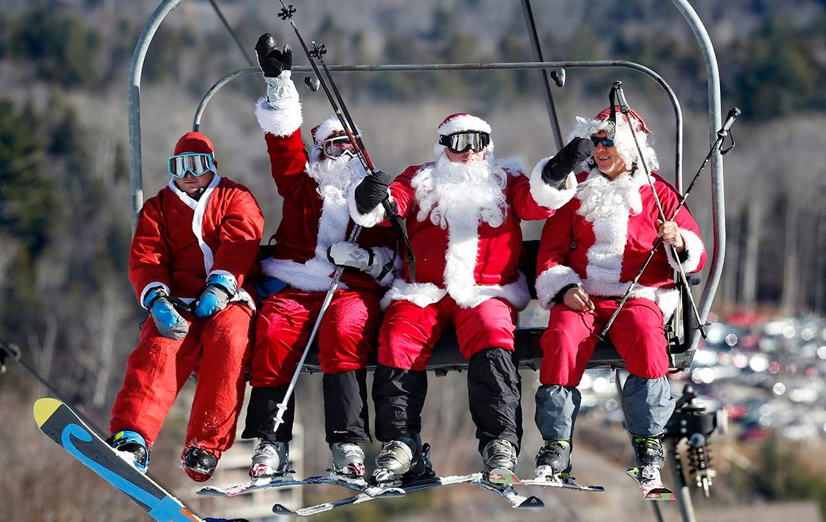 A snowboarder and skiers dressed as Santa bring the holiday spirit to the Sunday River ski resort, Sunday, Dec. 6, 2015, in Newry, Maine. The annual Santa Sunday fundraising event raised $3,014 for the Sunday River Community Fund.