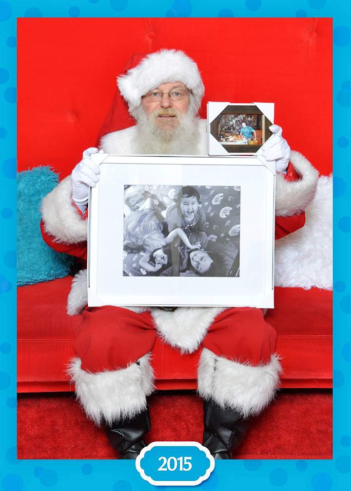 Santa Claus poses with a photograph of the Neville-Lake children and their grandfather.