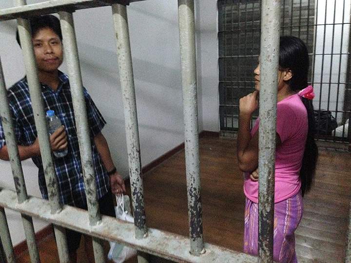 In this Friday, Nov. 13, 2015 photo, Burmese shrimp shed worker Tin Nyo Win, left, and his wife, Mi San, stand in a jail cell after they were arrested in Samut Sakhon, Thailand. Even after Tin Nyo Win became a whistleblower against the shrimp shed where they worked, the couple was fingerprinted and held on nearly $4,000 bail and charged with entering the country illegally and working without permits.