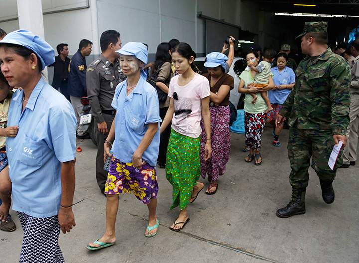In this Monday, Nov. 9, 2015 photo, Burmese workers are escorted by soldiers and police officers as they leave a shrimp shed after a raid conducted by Thailand’s Department of Special Investigation in Samut Sakhon, Thailand.
