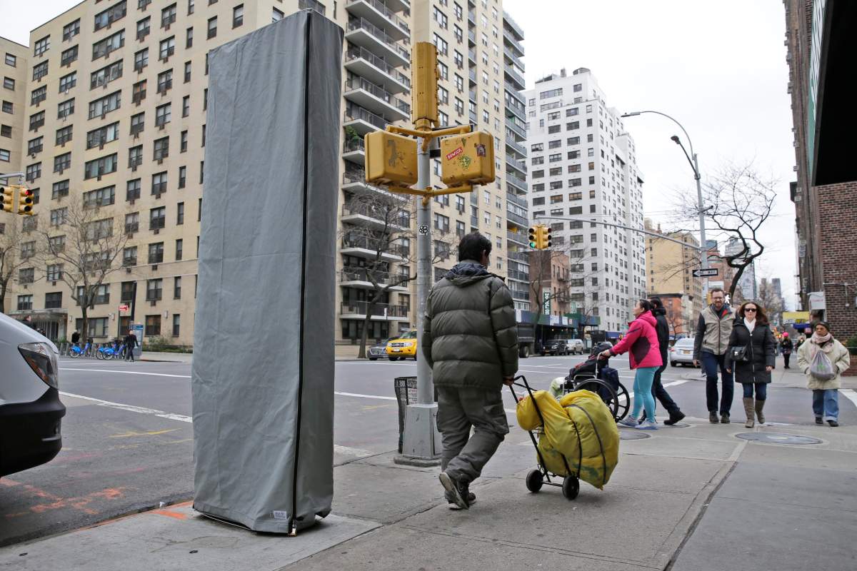 In this photo taken on Thursday, Dec. 31, 2015, people walk near a covered wireless kiosk at an intersection in New York. 