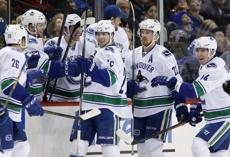 Teammates celebrate with Vancouver Canucks defenseman Ben Hutton (27) after he scored a goal in the second period of an NHL hockey game against the New York Islanders in New York, Sunday, Jan. 17, 2016.