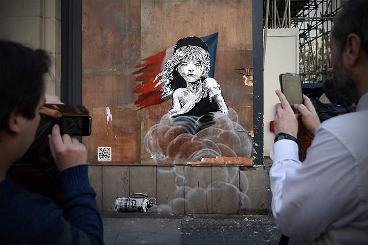 People photograph a Banksy artwork opposite the French embassy on January 25, 2016 in London, England.