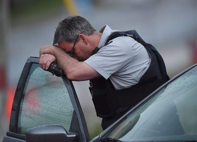 An RCMP officer rests his head at a roadblock in Moncton, N.B. on Thursday, June 5, 2014. 