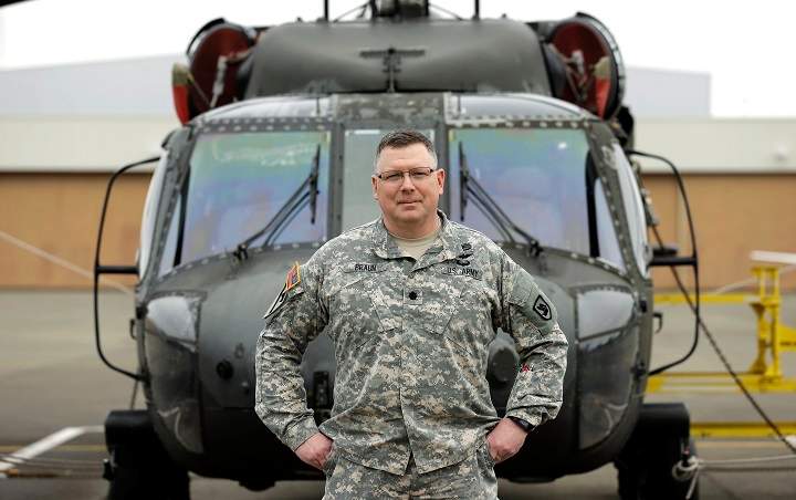 Lt. Col. Clayton Braun, of the Washington State Army National Guard, poses for a photo, Wednesday, Jan. 20, 2016, at Joint Base Lewis-McChord in Washington state in front of a military helicopter that could be used in response to a major earthquake. 