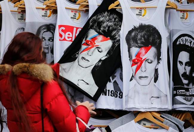 A woman looks at shirts with a portrait of David Bowie, in London, Monday, Jan. 11, 2016.