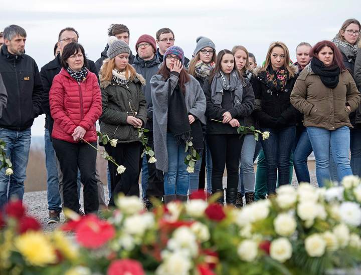 People hold flowers during a commemoration ceremony on International Holocaust Remembrance Day in the former Nazi concentration camp Buchenwald near Weimar, central Germany, on Wednesday, Jan. 27, 2016.