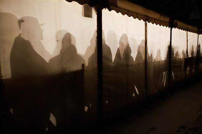 Migrants are silhouetted as they warm themselves inside a waiting tent to get an appointment at the central registration center for refugees and asylum seekers LaGeSo (Landesamt fuer Gesundheit und Soziales - State Office for Health and Social Affairs) in Berlin, Wednesday, Jan. 6, 2016. (AP Photo/Markus Schreiber).