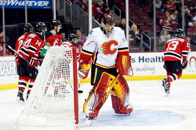 Calgary Flames goalie Jonas Hiller, center, of Switzerland, reacts after allowing New Jersey Devils right wing Lee Stempniak (20) to score a goal during the second period of an NHL hockey game, Tuesday, Jan. 19, 2016.