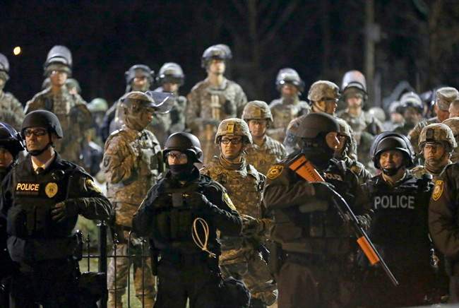 In this Friday, Nov. 28, 2014, file photo, police and Missouri National Guardsmen face protesters gathered in front of the Ferguson Police Department in Ferguson, Mo.