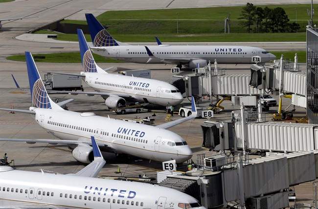 United Airlines planes are parked at their gates as another plane, top, taxis past them at George Bush Intercontinental Airport, in Houston.