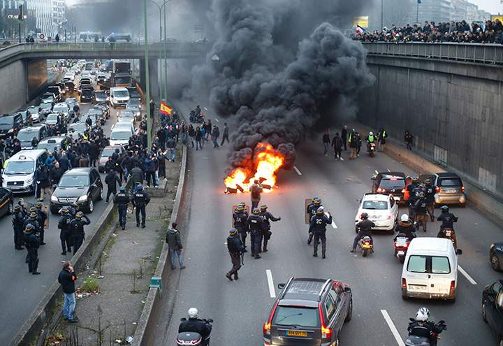 Anti-riot policemen arrive as taxi drivers block traffic during a demonstration) on January 26, 2016 in Paris.