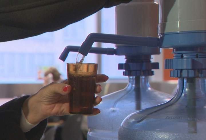 An employee drinks water from a bottle after black particles were found in the tap water at Sainte-Justine Hospital, Friday, January 29, 2016.