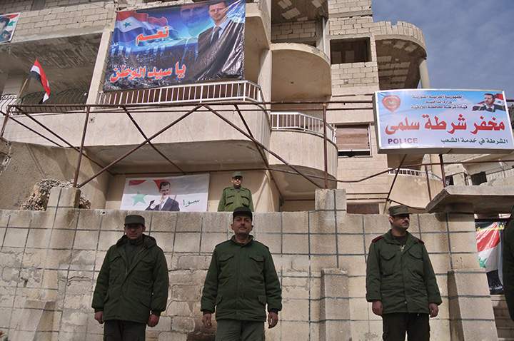 Syrian troops stand in front of a police station with a portrait of Syrian President Bashar Assad in Salma, Syria, Friday, Jan. 22, 2016. 
