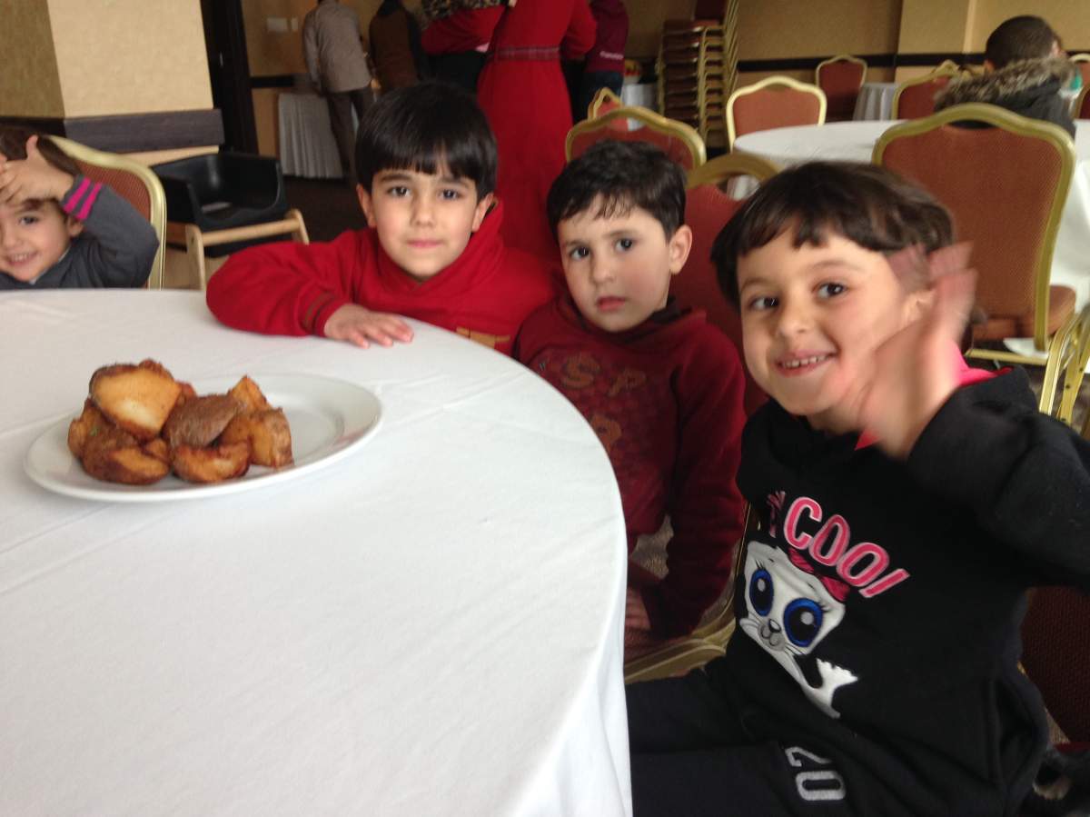 Syrian refugees wave to the camera at an Immigrant Services Association of Nova Scotia event on December 30, 2015.