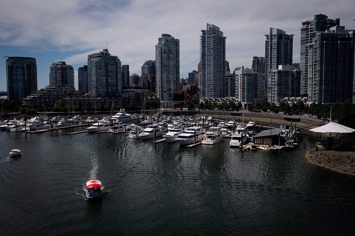 A water taxi travels on False Creek as boats are moored in a marina near Yaletown condo towers, in Vancouver, on July 13, 2014.