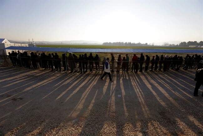 People form a line as they wait to receive food distributed by non-governmental organizations at a refugee camp in the northern Greek village of Idomeni Thursday, Jan. 21, 2016. About 1,000 refugees from Syria, Afghanistan and Iraq are stranded at Greece's northern border with Macedonia, after Macedonian authorities stopped letting them through citing problems with transit flows further north on the Balkan route which have caused a chain reaction. (AP Photo/Thanassis Stavrakis).