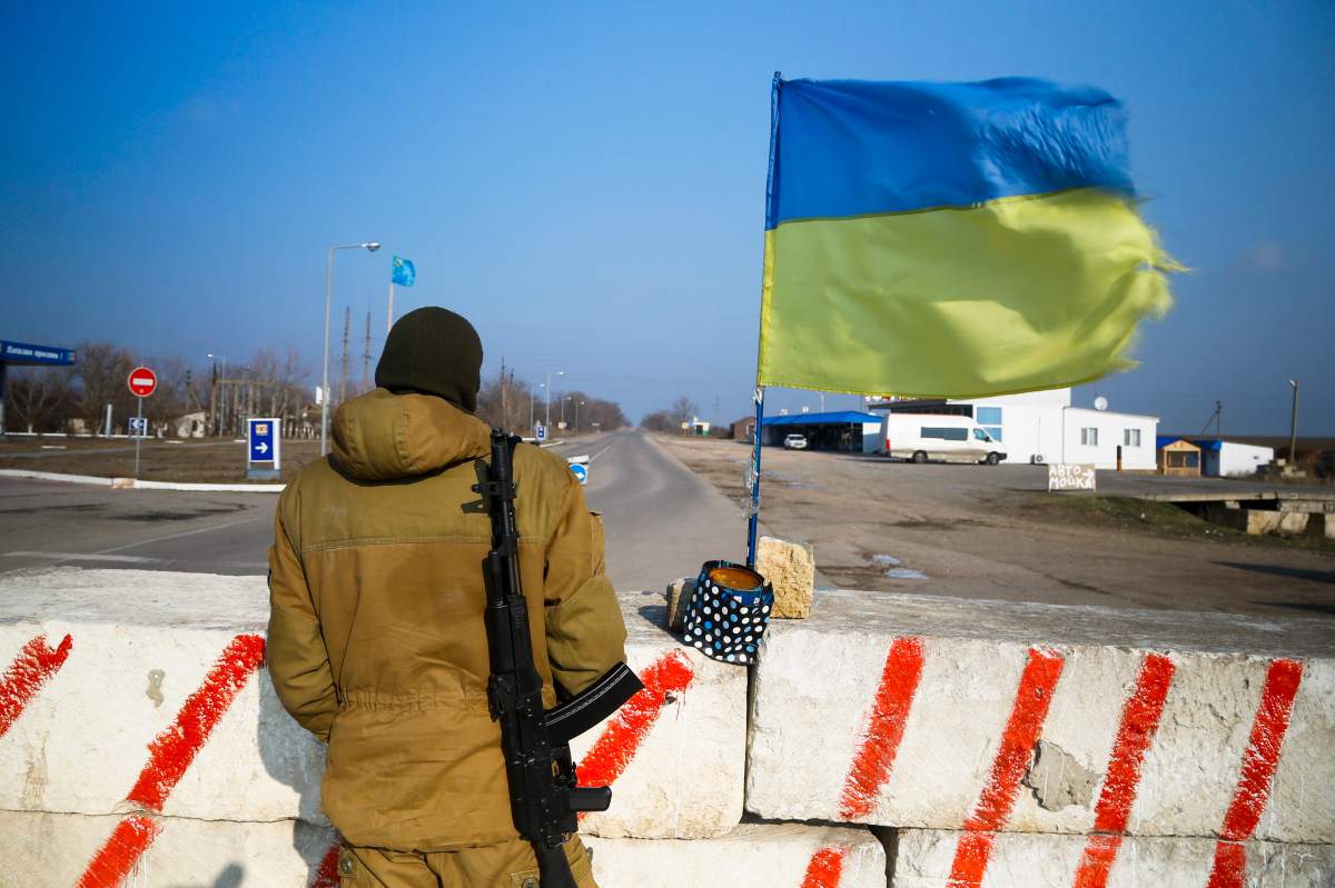 In this photo taken Saturday Jan. 23, 2016, a Crimean tatar activist stands guard at concrete blocks at a check-point in the village of Chonhar in the Kherson region in southern Ukraine close to the de-facto border with Crimea.  