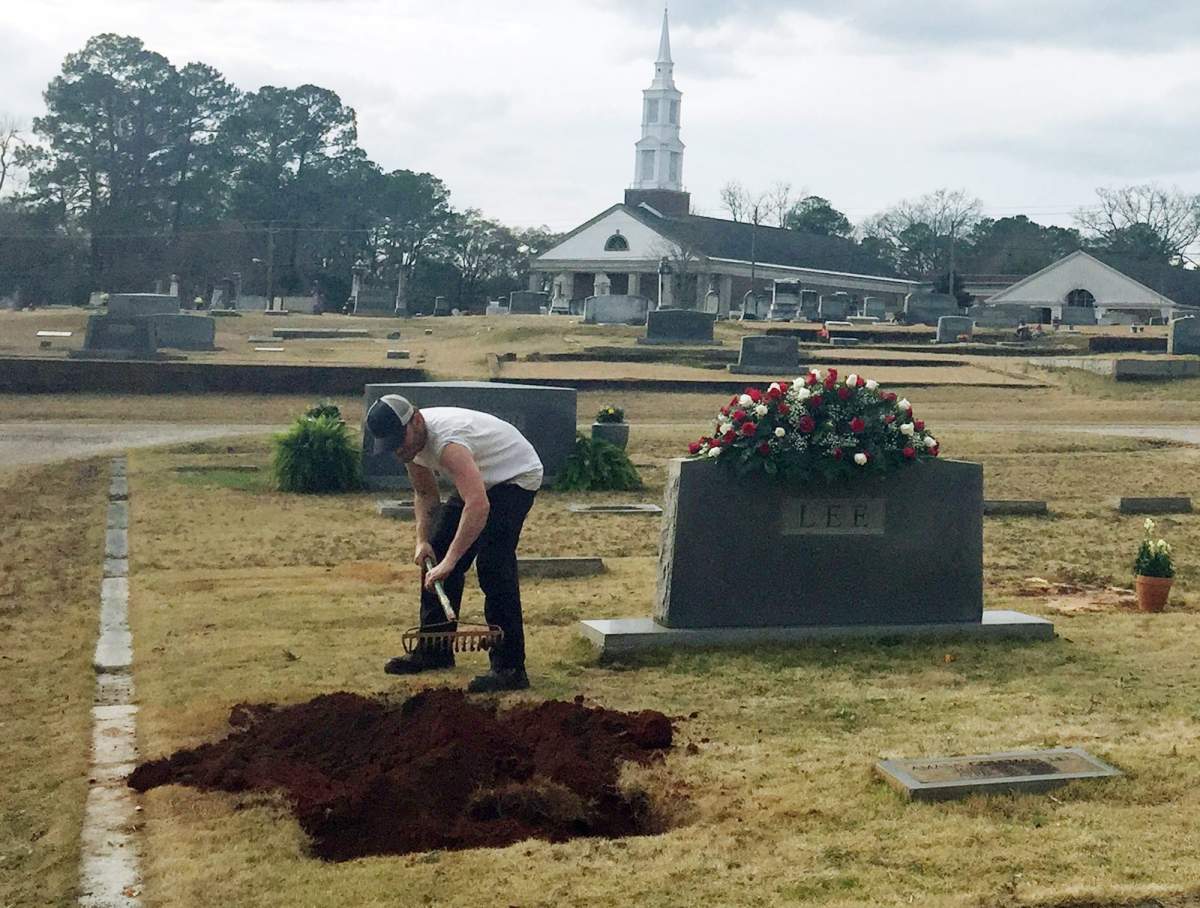 A man rakes soil over a grave in the Lee family cemetery plot, Saturday, Feb. 20, 2016, in Monroeville, Ala. Harper Lee, the author of “To Kill a Mockingbird,” died Friday, Feb. 19, 2016. She was 89. 