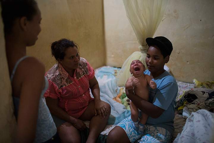 In this Jan. 30, 2016 photo, Solange Ferreira, left, watches as her nephew Jhonnata tries to calm Jose Wesley, in their house in Bonito, Pernambuco state, Brazil.