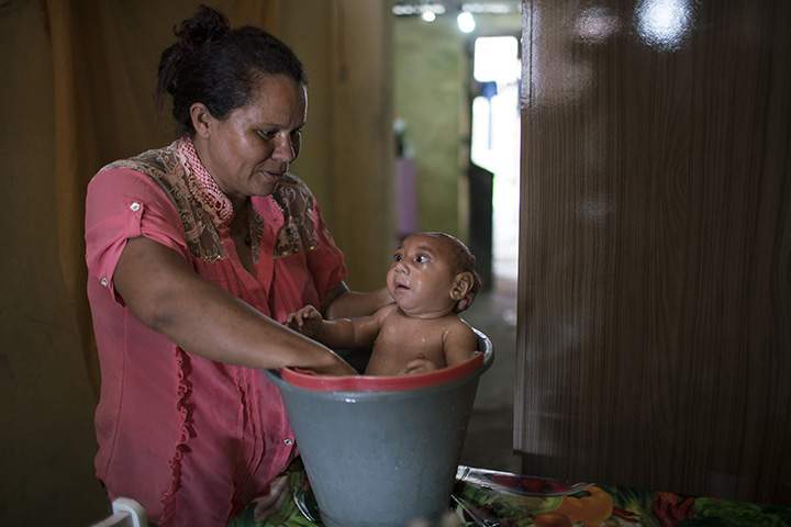 In the Jan. 30, 2016 photo, Solange Ferreira bathes her son Jose Wesley in a bucket at their house in Bonito, Pernambuco state, Brazil.
