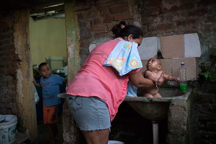 In this Jan. 30, 2016 photo, Solange Ferreira bathes Jose Wesley in a sink in their house in Bonito, Pernambuco state, Brazil.