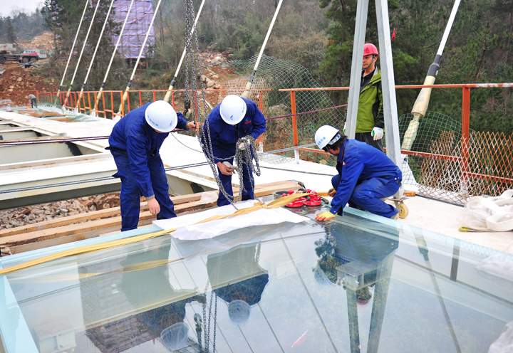 Workers install a piece of glass on a suspension bridge, about 300 metres above ground, at The Grand Canyon of Zhangjiajie on January 27, 2016 in Zhangjiajie, Hunan Province of China.