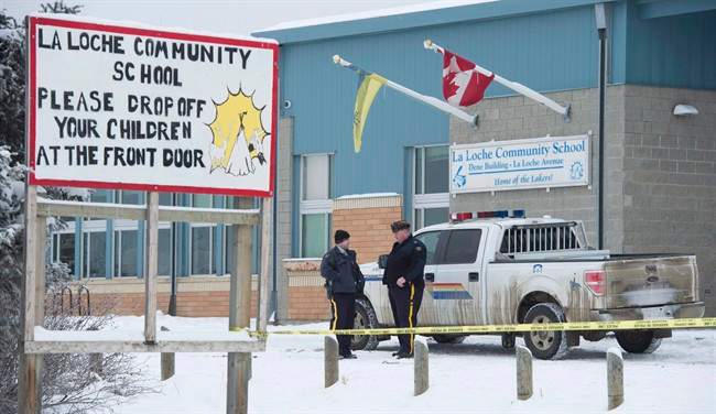 Members of the RCMP stand outside the La Loche Community School in La Loche, Sask. Monday, Jan. 25, 2016. 