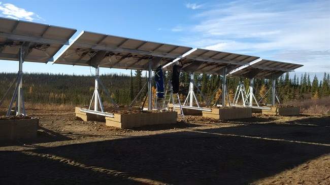 A worker adjusts one of the panels on a solar array installed in this tiny, remote northern community of Colville Lake, N.W.T., in this undated handout photo. Colville Lake expects to run entirely on the sun as summer returns – with batteries and a diesel generator as a backup.