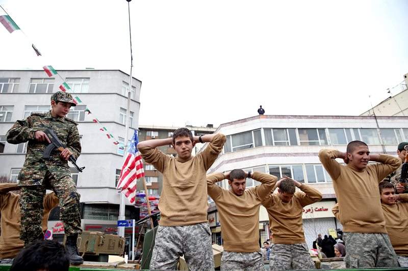 In this Thursday, Feb. 11, 2016 file photo, members of Iranian Basij paramilitary force re-enact the January capture of U.S sailors by the Revolutionary Guard in the Persian Gulf, in a rally commemorating the 37th anniversary of Islamic Revolution in Tehran, Iran.