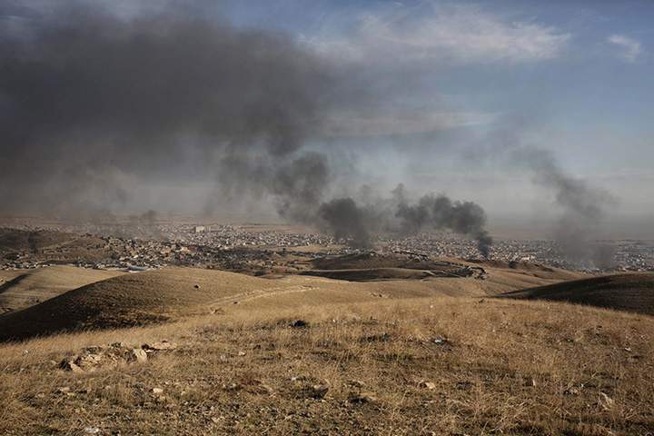 In this Nov. 12, 2015 file photo, smoke rises over Sinjar, northern Iraq from oil fires set by Islamic State militants as Kurdish Iraqi fighters, backed by U.S.-led airstrikes, launch a major assault. 