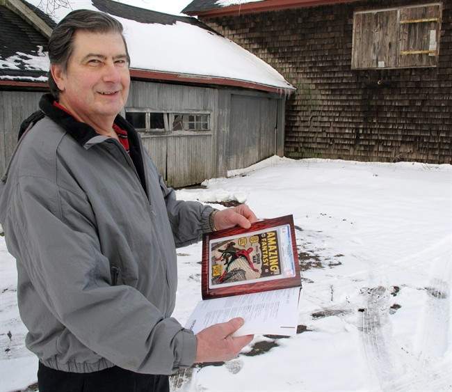 In this photo taken Tuesday, Feb. 9, 2016, in Calverton, N.Y., Walter Yacoboski holds an auction guide featuring one of his comic books, "Amazing Fantasy" No. 15, which features the Spider-Man character.