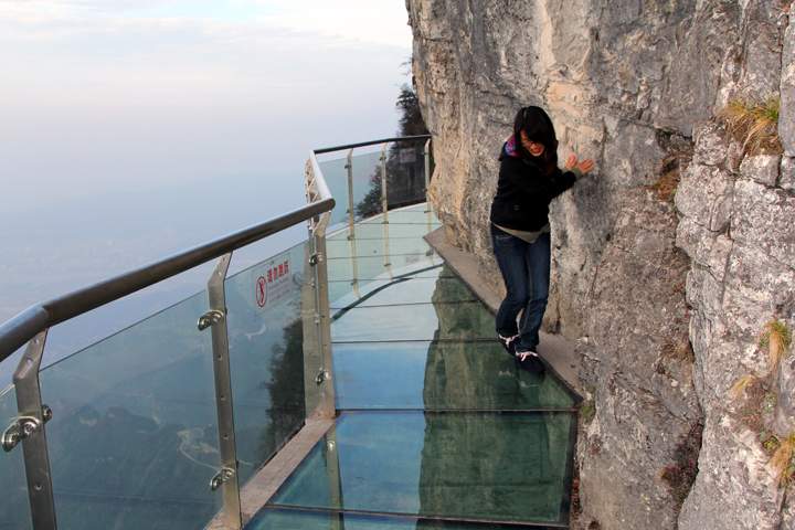 A tourist walks on a glass road alongside a cliff on Tianmen Mountain on November 9, 2011 in Zhangjiajie, Hunan Province of China.