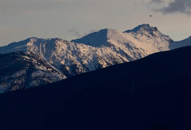 A helicopter flies past a mountain near McBride, B.C., on Saturday January 30, 2016.