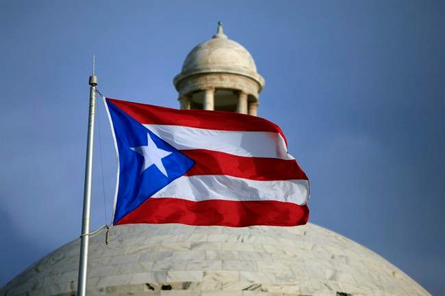In this Wednesday, July 29, file 2015 photo, the Puerto Rican flag flies in front of Puerto Rico’s Capitol as in San Juan, Puerto Rico.