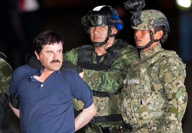 In this Jan. 8, 2016 file photo, Joaquin "El Chapo" Guzman is forced to face the press as he is escorted to a helicopter in handcuffs by Mexican soldiers in Mexico City.