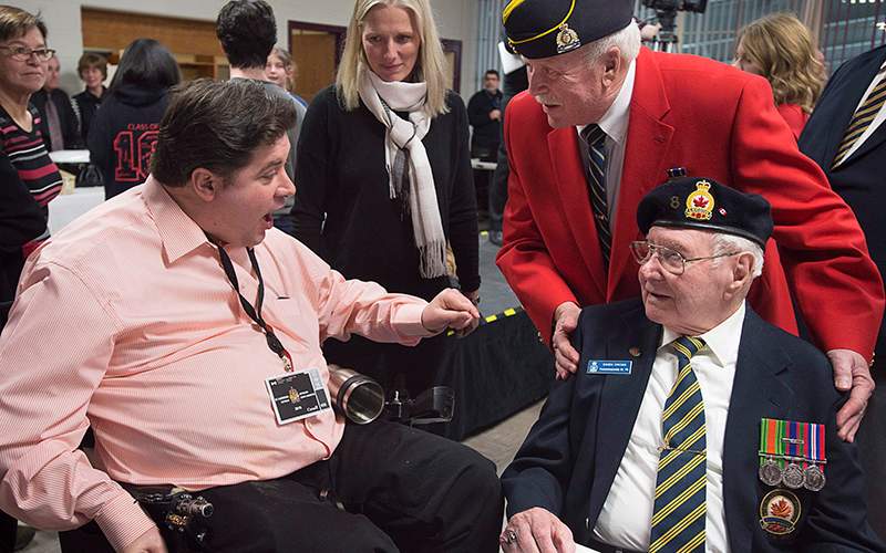 Veteran Affairs Minister Kent Hehr chats with veterans as Enviroment Minister Catherine McKenna, centre, looks on, as they attend a dinner at a local community centre in St. Andrews, N.B., on Monday, Jan. 18, 2016. 