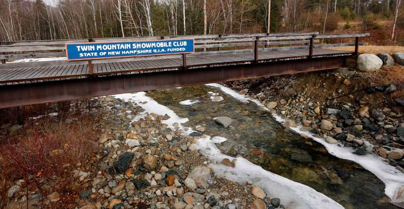 A bridge maintained by the Twin Mountain Snowmobile club is seen Wednesday Feb. 24, 2016, without any snow in Twin Mountain, N.H. It is part of thousands of miles of closed snowmobile trails in northern New England. 