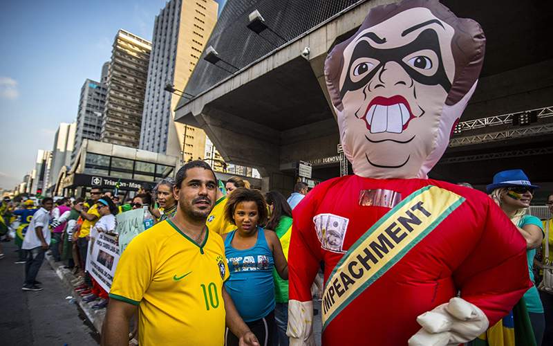Protesters stand next to a balloon with the effigy of President Dilma Rousseff on March 19 2016. Brazilian lawmakers relaunched impeachment proceedings against Rousseff and a judge blocked her bid to bring her powerful predecessor into her cabinet, intensifying the political crisis engulfing her.