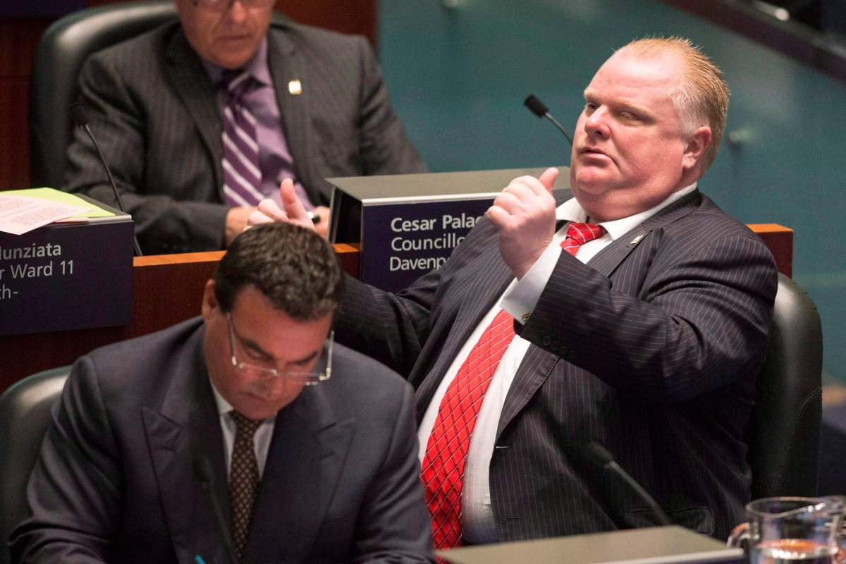 Toronto Mayor Rob Ford, right, gestures to Councillor Paul Ainslie in the council chamber as councillors look to pass motions to limit his powers in Toronto on November 18, 2013.