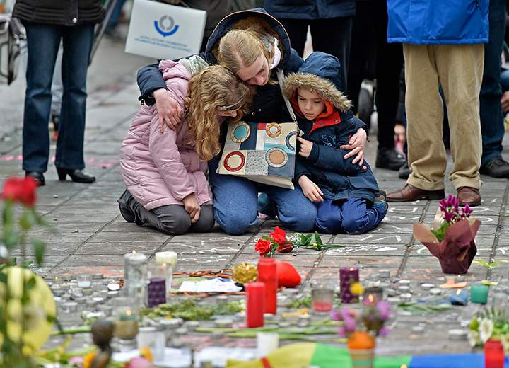 A woman and children sit and mourn at the Place de la Bourse in the centre of Brussels, for the victims of Tuesday’s bombings, on Wednesday, March 23, 2016.