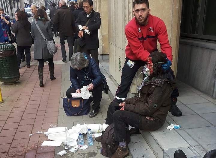 A private security guard helps a wounded women outside the Maalbeek subway station in Brussels on March 21, 2016 after a blast near the EU institutions.