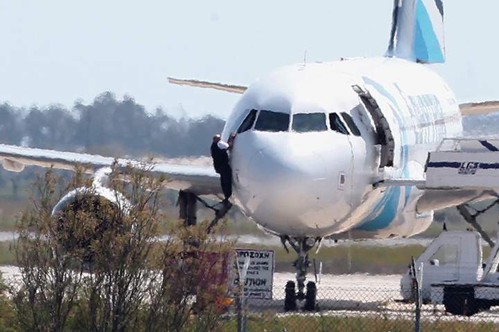A man leaves the hijacked aircraft of Egyptair from a cockpit window at Larnaca airport in Cyprus Tuesday, March 29, 2016.