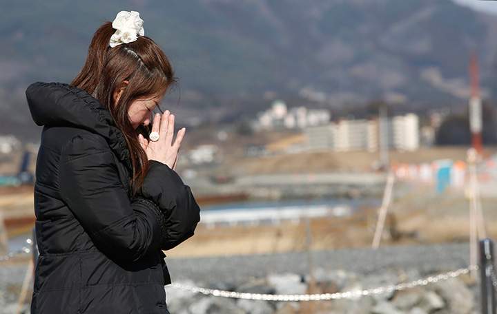 A woman prays in front of the lone pine tree that miraculously survived the deadly 2011 earthquake and tsunami among 70,000 trees along the coastline in Rikuzentakata, northeastern Japan, Friday March 11, 2016. 