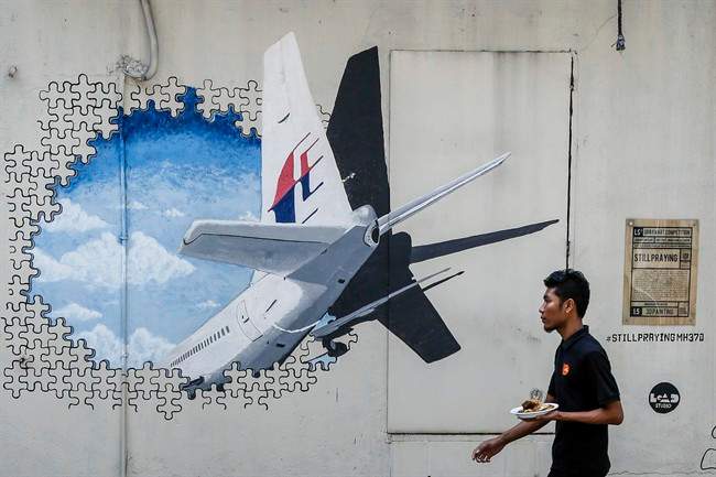 FILE – In this Tuesday, Feb. 23, 2016 file photo, a waiter walks past a mural of flight MH370 in Shah Alam outside Kuala Lumpur, Malaysia. South African authorities say debris found on a beach in Mozambique by a South African teenager will be sent to Australia to confirm if it is be part of missing Malaysia Airlines Flight 370, it was reported on Friday, March 11, 2016.