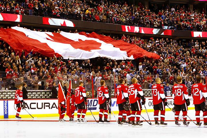 The Ottawa Senators stand at the blue line as the Canadian flag passes through the crowd prior to a game against the Vancouver Canucks on at Scotiabank Place on November 11, 2010 in Ottawa.  