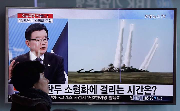 A woman passes by a TV screen showing file footage of the missile launch conducted by North Korea, at Seoul Railway Station in South Korea on Thursday, March 10, 2016. 