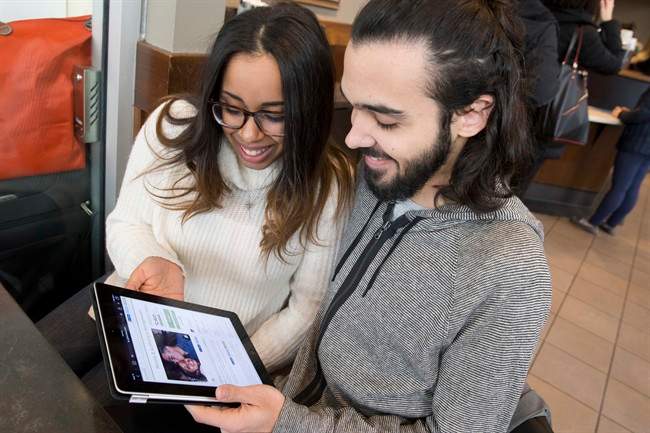 Nicole DePinto, left, and her husband, Anthony, pose for a photo with their crowdfunding page displayed on an iPad, in New York. 