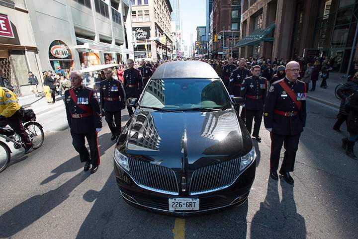 An honour guard escorts the hearse carrying the casket of former Toronto mayor Rob Ford from city hall during his funeral procession to St. James Cathedral in Toronto on Wednesday, March 30, 2016.
